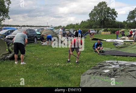 Zufällige Leute auf dem Campingplatz, die Zelte auf einem Feld aufstellen müssen Stockfoto