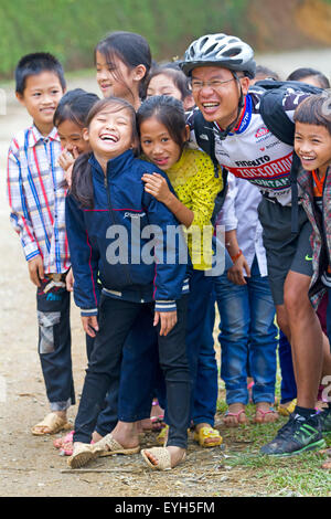 Radfahrer bei Schulkindern auf einer Straße in der Nähe von Cuc Phuong Nationalpark Stockfoto