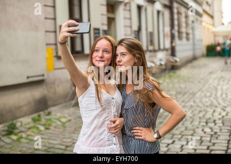 Zwei süße Teenager nehmen Selfie auf einem Smartphone auf der Straße des alten Stadtteils. Stockfoto