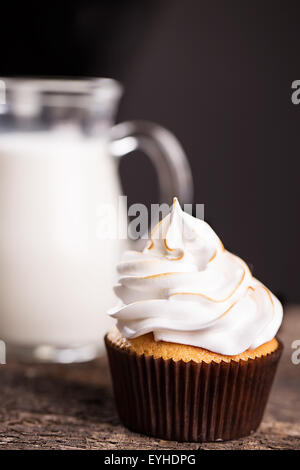 Leckere Muffins mit einer Karaffe Milch auf Holztisch Stockfoto