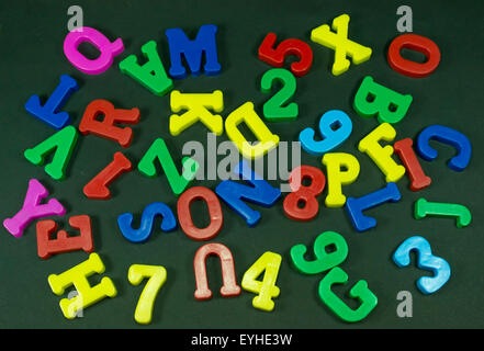 Kunststoff gefärbt, Zahlen und Buchstaben auf einem schwarzen Hintergrund zufällig platziert Stockfoto