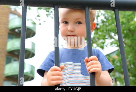 Porträt eines traurigen Kindes hinter Gittern Stockfoto