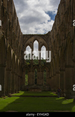 Der Blick aus dem Ende der Kapelle in Rievaulx Abbey bei strahlendem Sonnenschein durch die Bögen und Fenster scheint. Stockfoto