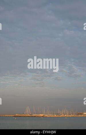 Erste Sonnenstrahlen schlagen die Masten in der Marina im Morgengrauen an der Playa de Palma in der Nähe von Can Pastilla, Mallorca Stockfoto