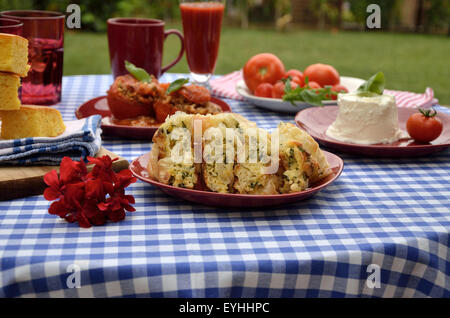 Mittagessen am blau-weißen Tischdecke mit heimischen Käse-Spinat-Torte, Maisbrot, gefüllte Tomaten und Käse Stockfoto