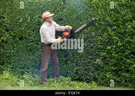 Mann trägt Schutzbrille und Handschuhe Garten schneiden Absicherung mit einem Benzin-Hedge-cutter Stockfoto