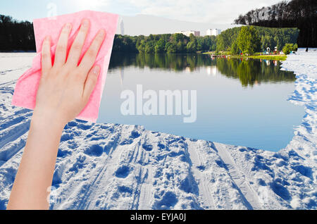 Saison Konzept - Hand löscht Schneefeld auf zugefrorenen Fluss von rosa Tuch aus Bild und Sommer Ufer erscheint Stockfoto