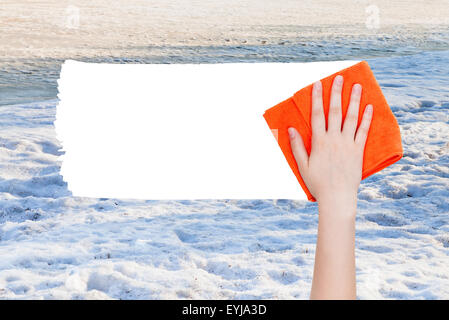 Saison Konzept - Hand löscht Winterschnee von orange Lappen aus Bild und weißem leeren textfreiraum erscheinen Stockfoto
