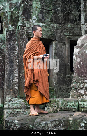 SIEM REAP, Kambodscha - 30. Oktober 2014: Buddhistischer Mönch sticht die verwitterten Tempelarchitektur am Bayon in Angkor Wat. Stockfoto