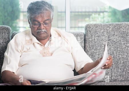 Älteren indischen Mann liest Zeitung zu Hause. Asiatische Senioren leben Lebensstil im Innenbereich. Stockfoto