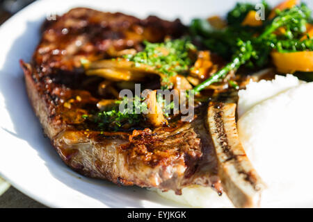 Nahaufnahme eines Knochens im Rib-Eye, serviert mit Broccolini und Kartoffelpüree Stockfoto