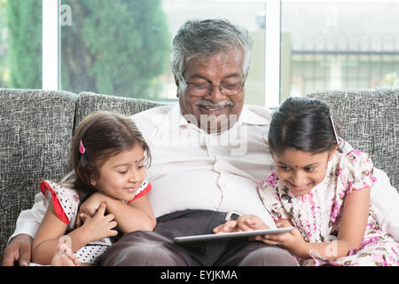Moderne Technologie-Konzept. Großeltern und Enkelkinder mit touch Screen Tablet-Computer. Porträt-indische Familie zu Hause. ASI Stockfoto