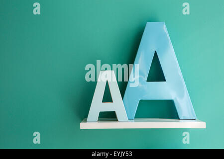 Buchstaben "eine kleine und große Größe Türkis Farbe auf einem weißen Regal". Stockfoto