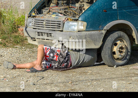 Der Mann repariert das Auto, darunter liegenden Stockfoto