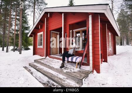 Porträt des jungen Skifahrerin Kaffeetrinken auf Kabine Veranda, Posio, Lappland, Finnland Stockfoto