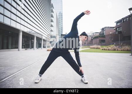 Junge männliche Läufer Strecken in der Stadt Stockfoto