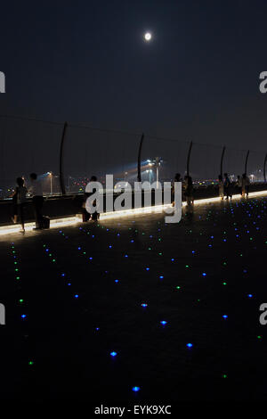 Menschen beobachten Vollmond, wie es über die Skyline von Haneda Airport Terminal 2 am 31. Juli 2015, Tokyo, Japan steigt. Dies ist der zweite Vollmond im Juli und ist bekannt als ein Blue Moon. Es wurde kein zweite Vollmond in einem Monat seit August 2012 und andern bis Januar 2018 wird es nicht geben. © Rodrigo Reyes Marin/AFLO/Alamy Live-Nachrichten Stockfoto