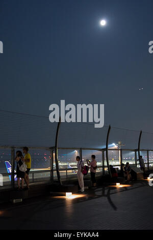 Menschen beobachten Vollmond, wie es über die Skyline von Haneda Airport Terminal 2 am 31. Juli 2015, Tokyo, Japan steigt. Dies ist der zweite Vollmond im Juli und ist bekannt als ein Blue Moon. Es wurde kein zweite Vollmond in einem Monat seit August 2012 und andern bis Januar 2018 wird es nicht geben. © Rodrigo Reyes Marin/AFLO/Alamy Live-Nachrichten Stockfoto