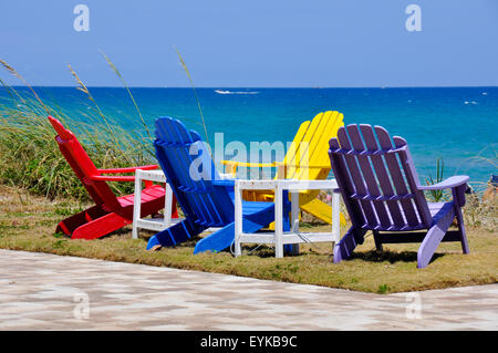 Vier bunte Adirondack Stühle mit Blick auf das Meer und den Strand von Fort Lauderdale, Florida. Stockfoto