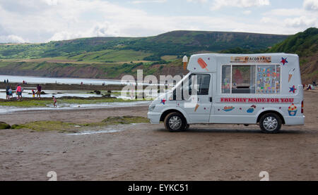 Eiswagen am Strand von Robin Hoods Bay, in der Nähe von Whitby North Yorkshire, England UK mit Felsen und Hügeln im Hintergrund. Stockfoto