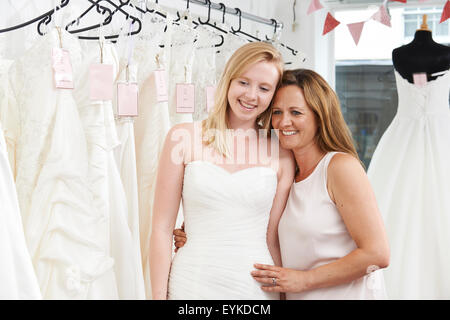 Mutter hilft Tochter Kleid In Bridal Shop wählen Stockfoto