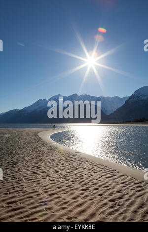 Sunburst über eine Alaska-Strand mit Bergen und ein Fotograf am Ufer. Stockfoto