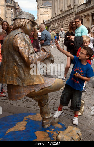 Masse der Touristen betrachten eine lebende Statue balancieren auf einem Bein im Zentrum von Bath, Bath Spa Somerset England UK Stockfoto