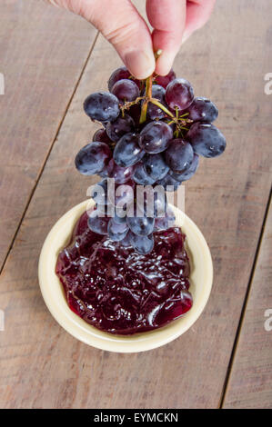 Trauben in eine Schüssel mit Traubengelee gesenkt Stockfoto