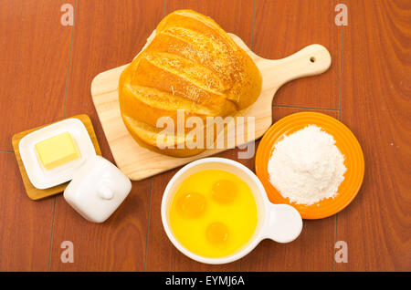 Wunderschöne farbige Brotlaib auf Holzoberfläche neben weiße Schüssel mit Eiern, Käse und Mehl gelegt. Stockfoto