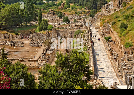 Hauptstraße von Ephesus, Selcuk, Kusadasi, Türkei, mit dem Marktplatz oder Agora auf der linken Seite. Großes Amphitheater ist oben rechts. Stockfoto