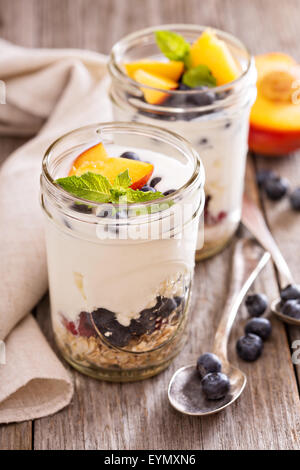 Geschichtete Frühstück Parfait mit Müsli, Pfirsiche oder Beeren Stockfoto