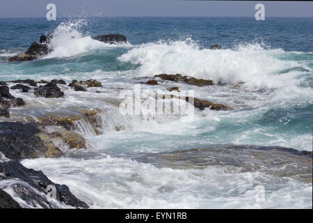 Wellen auf den Felsen. Weißen Surf und blaues Meer und Himmel an einem Sommertag. Stockfoto