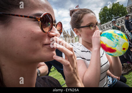 London, Großbritannien. 1. August 2015. Mitkämpfer inhalieren mit Lachgas Luftballons aufgeblasen, allgemein bekannt als "lachgas" hoch während einer Protestaktion von Westminster Parliament Square gegen einen Gesetzentwurf, der darauf abzielt, zu machen Verkauf illegaler psychoaktiver Substanzen zu erhalten. Credit: Guy Corbishley/Alamy leben Nachrichten Stockfoto