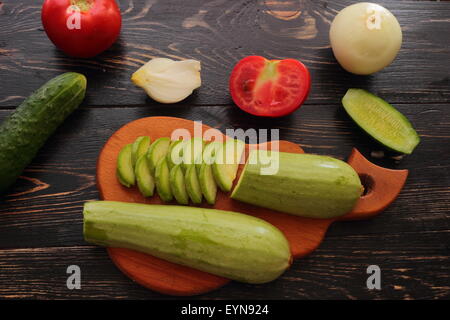 ganze und geschnittene Gurken Tomaten Zucchini Zwiebeln Stockfoto