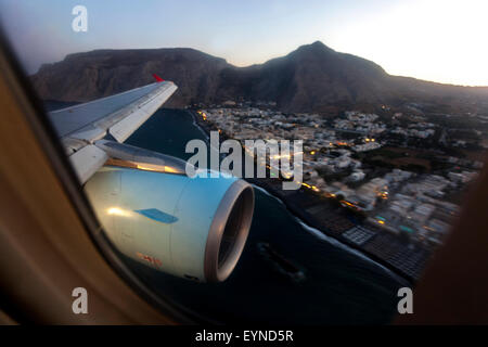 Luftfensteransicht von Motor und Flügel bei der Landung auf dem Flughafen Santorini (JTR) über der Küste Kamaris in der Abenddämmerung, Santorin, Griechenland Stockfoto