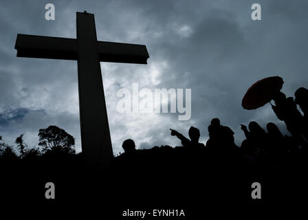 Silhouette von Besuchern und ein hohes christliches Kreuz im Bukit Kasih (Hügel der Liebe), einem beliebten religiösen Reiseziel in North Sulawesi, Indonesien. Stockfoto