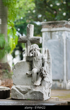 Statue eines trauernden kleinen Jungen, der Blumen auf einem christlichen Grabstein im Taman Prasati Museum (Museum des Gedenksteinparks) in Jakarta, Indonesien hält. Stockfoto