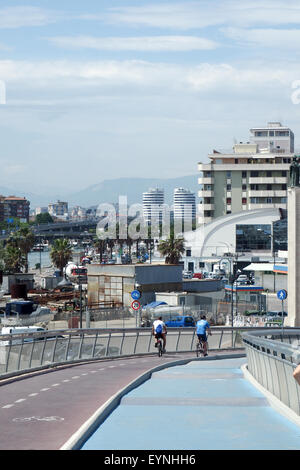 Zwei Radfahrer fahren auf der Ponte del Mare mit der Stadt Pescara im Hintergrund. Stockfoto