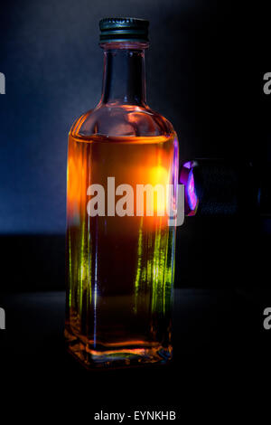 UV-Licht strahlt in eine kleine Flasche Olivenöl. Das Chlorophyll in das Olivenöl bewirkt, dass die rote Fluoreszenz Stockfoto