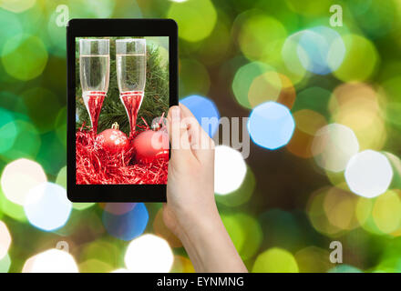 Mann nimmt Foto von Weihnachten Stillleben - zwei Gläser Sekt mit roten Xmas Kugeln und Lametta auf grüne unscharfe Christus Stockfoto