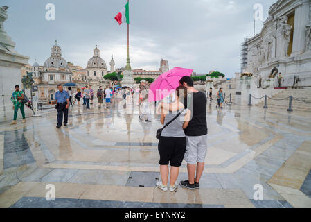 Paar Stockschirm, unter einer rosa Regenschirm ein junges Paar Pause eine Karte auf einem Regen zu lesen - fegte Terrasse des Vittorio Emanuele Monument in Rom, Italien Stockfoto