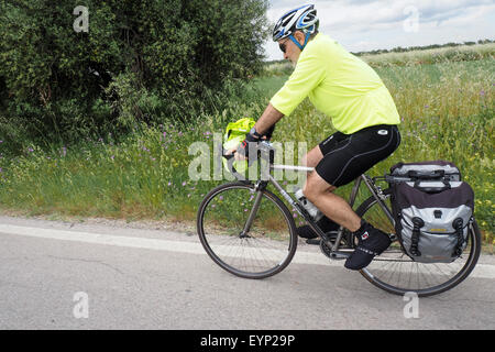 Ein touring Radsportler auf seinem Fahrrad auf einer Landstraße. Stockfoto