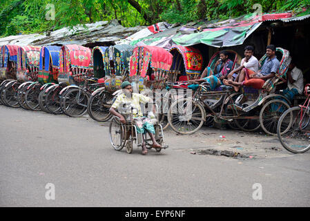 Bangladeshi Rikschafahrer warten auf Passagiere neben einem deaktivieren gehen mit Rollstuhl in Dhaka. Bangladesch. Am Juli 2015 migrieren Tausende von Menschen aus dem Land in die Hauptstadt Dhaka als Rikscha-Fahrer zu arbeiten, da sie keine Arbeit in ihren Dörfern während der drei-bis sechsmonatigen Monsun-Saison haben. Jede Rikschafahrer verdienen oft weniger als US$ 4 pro Tag. Stockfoto