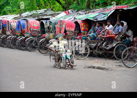 Bangladeshi Rikschafahrer warten auf Passagiere neben einem deaktivieren gehen mit Rollstuhl in Dhaka. Bangladesch. Am Juli 2015 migrieren Tausende von Menschen aus dem Land in die Hauptstadt Dhaka als Rikscha-Fahrer zu arbeiten, da sie keine Arbeit in ihren Dörfern während der drei-bis sechsmonatigen Monsun-Saison haben. Jede Rikschafahrer verdienen oft weniger als US$ 4 pro Tag. Stockfoto