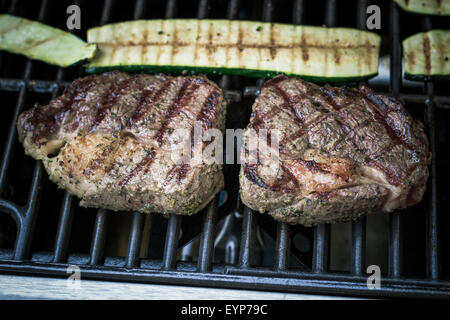 Zwei Rippenstück mit Zucchini auf Grill, Weichzeichner, Ansicht von oben Stockfoto