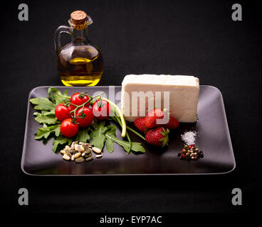 Zutaten für Erdbeer-Tomaten-Salat mit Feta-Käse, Olivenöl auf schwarz Stockfoto