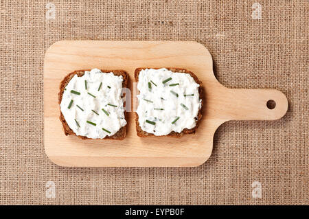 Zwei Scheiben würzigen Butterbrot mit grünen Zwiebeln obendrauf auf Holzbrett Stockfoto