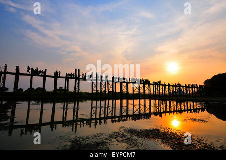 Einheimische und Touristen gehen über die berühmte 1,2 Kilometer lange U Bein Teak Bridge SpanningTaungthaman Lake bei Sonnenuntergang Amarapura, nr Mandalay, Myanmar Stockfoto