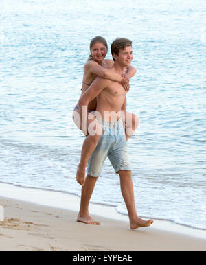 Glückliches junges Paar Spaß zusammen in den Sommerferien. gut aussehender Mann mit seiner Freundin Huckepack Stockfoto