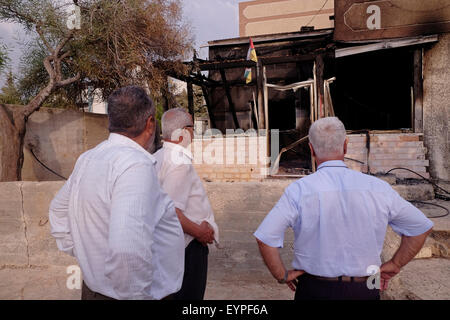 Palästinenser sehen das abgebrannte Haus der Dawabsha-Familie in Duma, einer palästinensischen arabischen Stadt im Westjordanland, die am 31. Juli von maskierten Angreifern in einem scheinbaren Preisschild-Angriff bombardiert wurde, bei dem der 18 Monate alte Ali Saad Dawabsha getötet und seine Eltern und sein 4-jähriger Bruder am 02. August 2015 schwer verletzt wurden. „Price Tag“ wird verwendet, um politische Gewaltakte zu bezeichnen, die von rechtsgerichteten Israelis verübt werden, die gegen die Politik der israelischen Regierung in Bezug auf die Siedlungen und die Palästinenser protestieren. Stockfoto